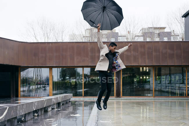 Retrato de hombre negro elegante con abrigo gris y paraguas en la calle - foto de stock