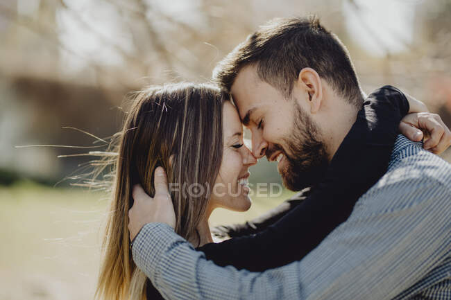 Bärtiger Mann umarmt lachende Frau, während er Zeit auf grünem Rasen auf der Straße verbringt — Stockfoto