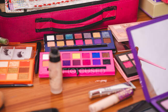 De cima paletas de sombras brilhantes multicoloridas colocadas perto de vários suprimentos cosméticos na mesa no estúdio — Fotografia de Stock