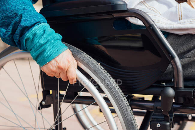 Ritagliato donna anziana irriconoscibile in sedia a rotelle lungo argine vicino al mare e godersi la giornata estiva — Foto stock