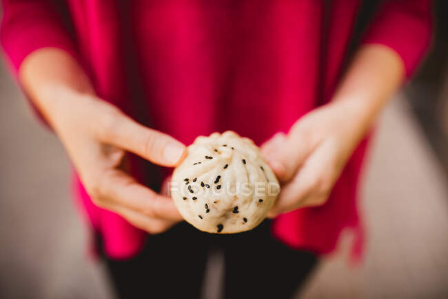 Unrecognizable female showing yummy Sheng Jian Bao to camera while standing on street — Stock Photo