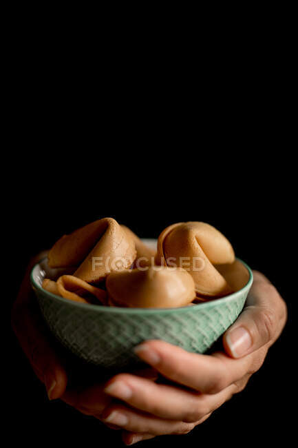 Closeup hands of anonymous woman holding small bowl full of crispy fortune cookies — Stock Photo