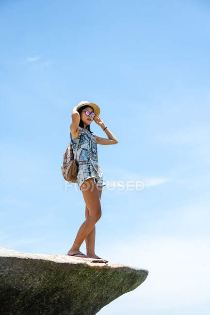 Menina asiática bonita de pé sobre as rochas, desfrutando do litoral no dia ensolarado do verão — Fotografia de Stock