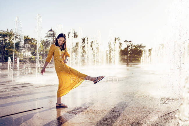 Повний вигляд веселої жінки в стильній сукні, насолоджуючись прісною водою Фонтану Палацу Еміратів в Абу-Дабі під час літніх канікул в Еміратах. — стокове фото