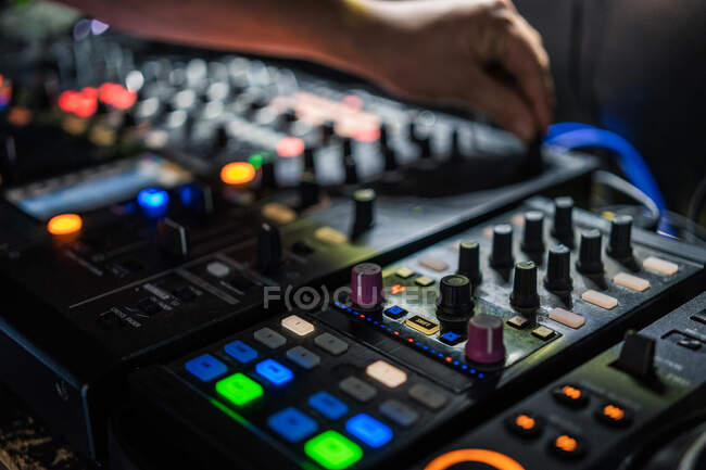 Desde arriba hombre de la cosecha jugando profesional de dos canales DJ controlador mientras se realiza en concierto en el club nocturno moderno - foto de stock