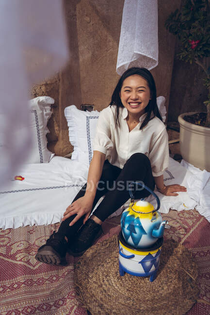 Porträt einer asiatischen Frau, die sich neben einem Wasserkocher auf dem Boden entspannt. Teeladen im historischen Viertel Al Fahidi — Stockfoto