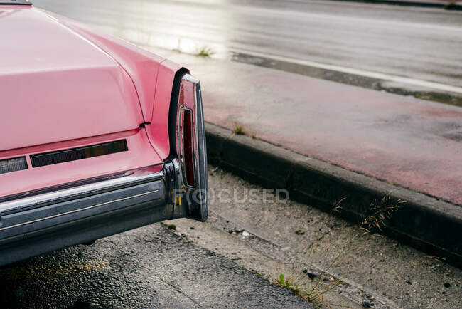 Desde arriba detalle de enfoque trasero de un coche clásico de color rosa en el suelo de asfalto - foto de stock