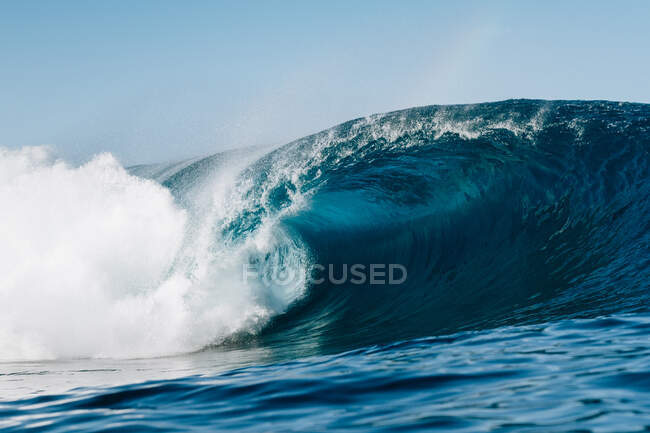 Potentes olas marinas espumosas rodando y salpicando sobre la superficie del agua contra el cielo azul - foto de stock