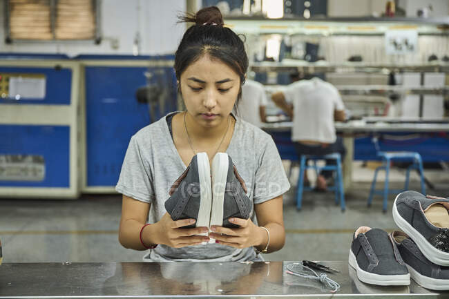 Empleado haciendo control de calidad en fábrica de zapatos chinos - foto de stock