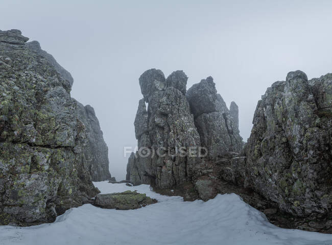 Montagnes rocheuses couvertes de brume et de neige contre un ciel nuageux en hiver dans le parc national de Guadarrama à Madird, Espagne — Photo de stock