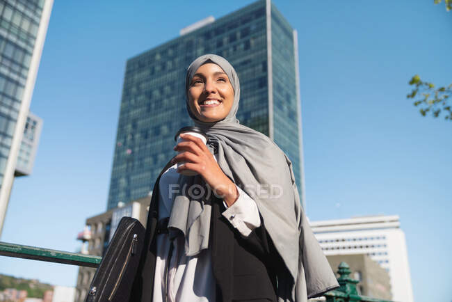Da sotto imprenditrice musulmana allegra in hijab e con caffè da asporto in piedi in strada — Foto stock