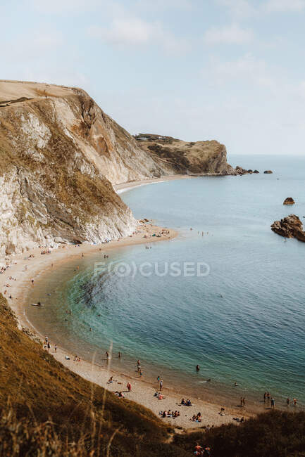 De cima paisagem marinha idílica com rochas chamadas Durdle Door e pessoas relaxando na praia no dia de verão — Fotografia de Stock