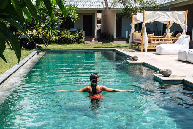 Обратный вид на анонимную туристку в купальнике, купающуюся в бассейне во время летней поездки — стоковое фото