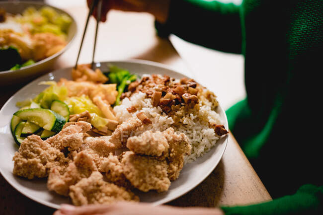 Анонимные в повседневной одежде едят вкусное тайваньское бенто с палочками в азиатском кафе — стоковое фото