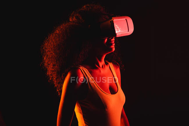 Femme anonyme ethnique explorant la réalité virtuelle dans un casque sur fond noir — Photo de stock