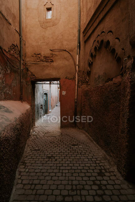 Rue étroite avec chaussée en pierre et murs de bâtiments altérés à Marrakech, Maroc — Photo de stock