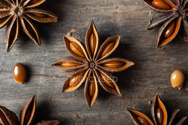 Крупним планом ароматичні висушені зірки анісу з насінням, розкиданими на сільському дерев'яному столі для гастрономічного концепту фону — стокове фото