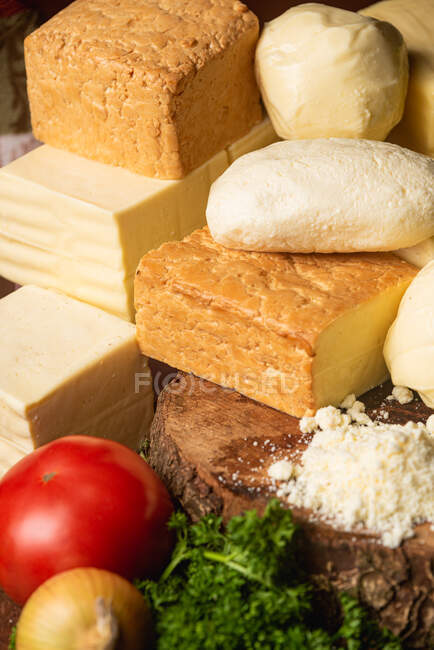 Collection of Italian cheese on table with fresh vegetables and curly parsley with basil leaves on spatulas — Stock Photo