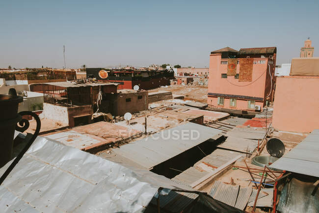 Telhados sujos de casas intempéries contra céu azul sem nuvens em pobre distrito de Marraquexe, Marrocos — Fotografia de Stock