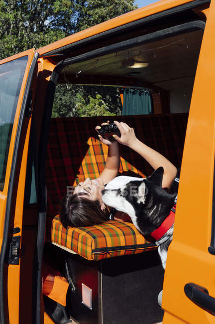 Вид сбоку женщины, лежащей в фургоне и просматривающей снимки на фотокамеру во время летних каникул — стоковое фото