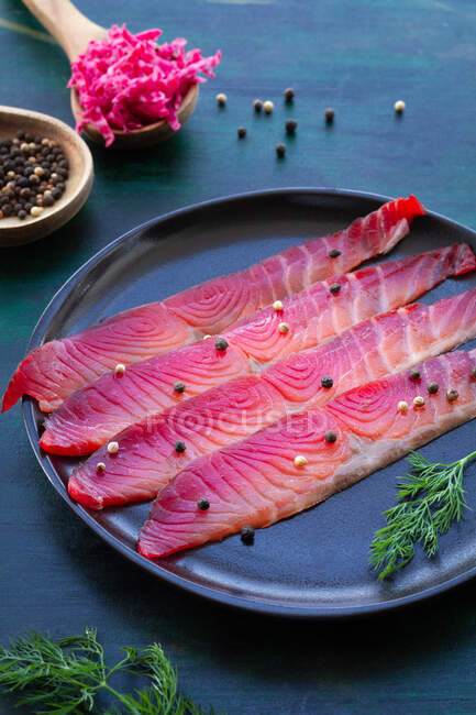 From above gravlax with mixed peppercorns and fresh dill sprigs on plate on dark background — Stock Photo
