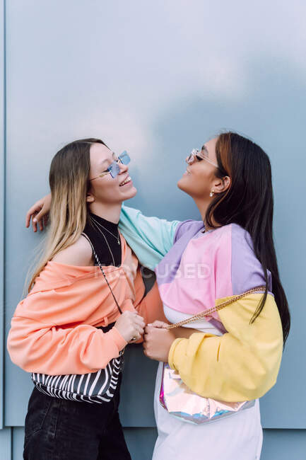 Side view of girlfriends in stylish sunglasses with long hair making giving air kiss to each other — Stock Photo