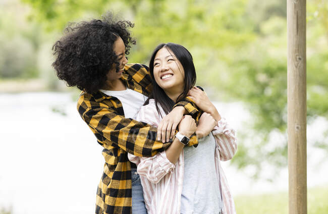 Cheerful multiracial couple of lesbian women embracing in woods and enjoying weekend — Stock Photo