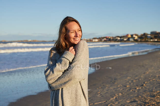 Спокойная самка наслаждается закатом летом на пляже у моря, глядя в сторону — стоковое фото