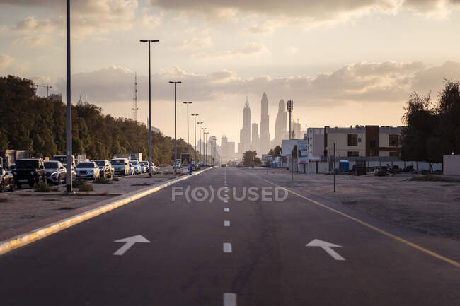 Avenida vazia ao pôr do sol em direção à Marina do Dubai com edifícios ao fundo — Fotografia de Stock