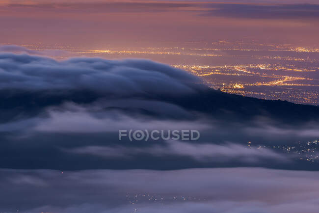 Aerial view of modern city of Madrid in Spain and mountains covered with tick clouds under colorful sky during sunrise in Guadarrama National Park — Stock Photo