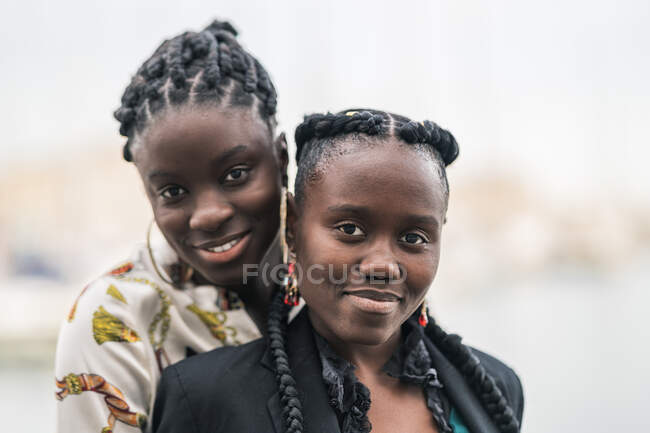 Conteúdo senhoras afro-americanas elegantes que ficam perto e olham para a câmera com um sorriso atencioso no parque em um dia brilhante — Fotografia de Stock