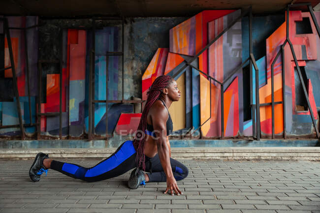 Femme ethnique étirant la jambe — Photo de stock