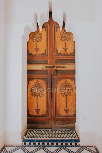 Porta pintada Shabby localizada atrás do arco esculpido do antigo edifício árabe em Marraquexe, Marrocos — Fotografia de Stock