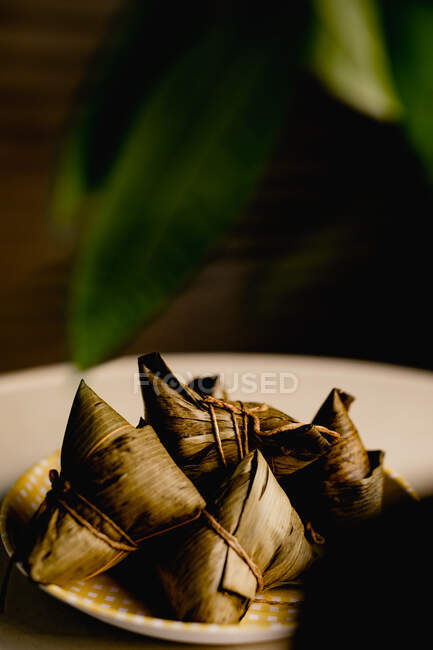 Opened and covered bamboo leaf rice dumplings placed on cute checked plate — Stock Photo