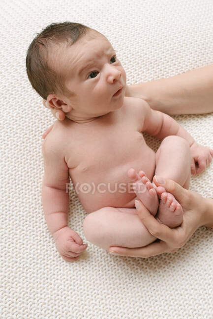 D'en haut de la récolte méconnaissable mère aimante regardant adorable bébé nu sur le lit à la maison — Photo de stock