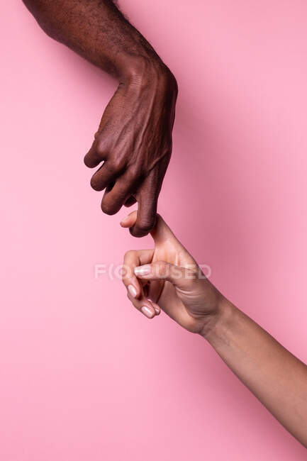 Visão de close-up da mulher branca e do homem negro de mãos isoladas no fundo marrom escuro; conceito de unidade e inclusão — Fotografia de Stock