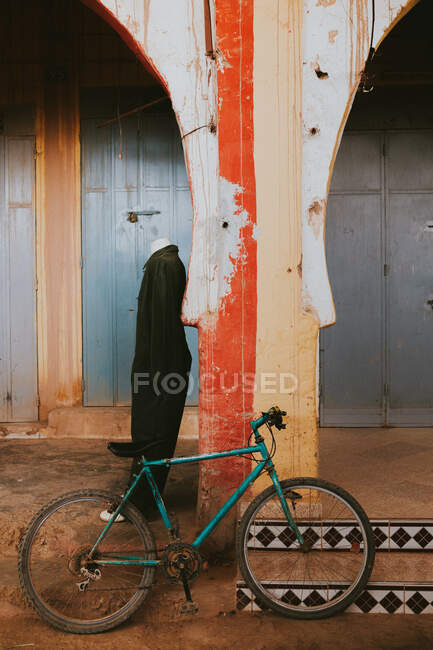 Bicicleta envelhecida colocada perto de manequim e resistiu construção de loja de roupas na rua de Marraquexe, Marrocos — Fotografia de Stock