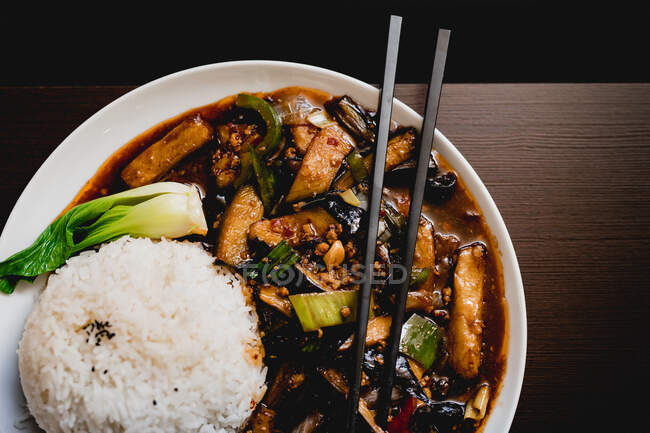 Vista aerea di appetitose melanzane Yuxiang cotte con verdure sane e riso su piatto bianco nel ristorante asiatico — Foto stock