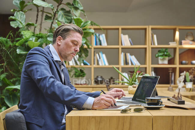 Designer at his desk working on his computer using his tablet — Stock Photo