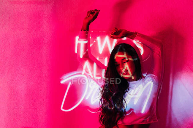 Giovane donna ispanica con gli occhi chiusi appoggiata al muro vicino al neon Era tutto iscrizione da sogno — Foto stock