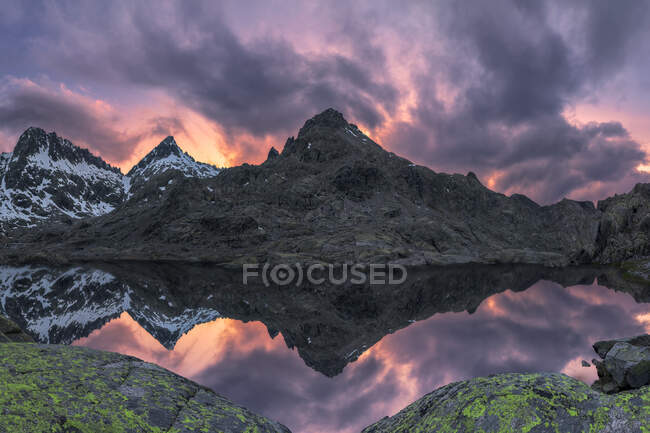 Paisagem espetacular de montanhas cobertas de neve ao pôr do sol refletida em um lago — Fotografia de Stock