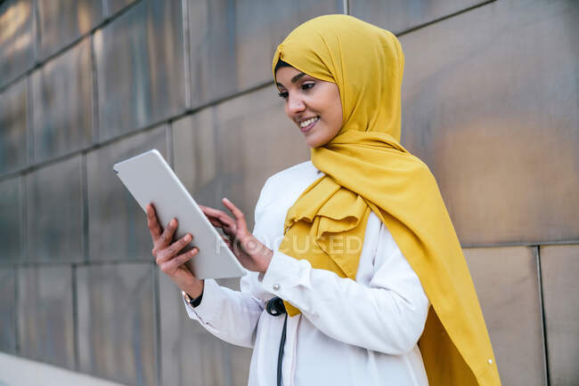 Усмішка мусульманки-підприємці в жовтому хіджабі стоять на вулиці і переглядають табличку — стокове фото