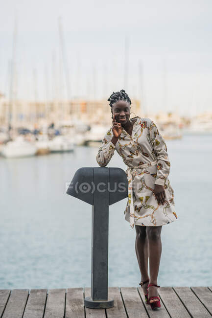 Elegante mujer afroamericana hermosa pensativa con trenzas africanas sonriendo mirando a la cámara en el parque - foto de stock