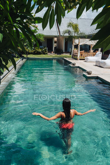 Vista posteriore di turista anonima in costume da bagno nuoto in piscina increspata durante il viaggio estivo — Foto stock