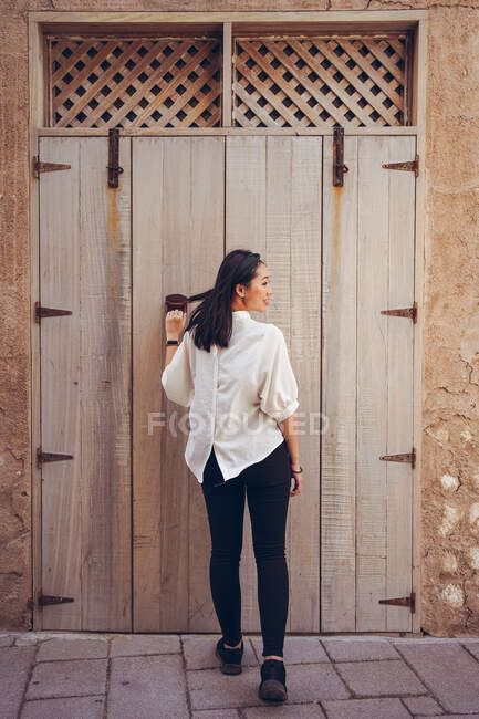 Vue arrière du voyageur féminin en tenue décontractée tout en ouvrant la porte lors d'une visite guidée dans le quartier historique d'Al Fahidi à Dubaï — Photo de stock