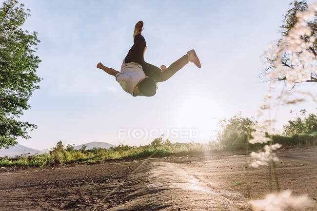 Акробатичний чоловік стрибає над землею і виконує небезпечний трюк у сонячний день — стокове фото