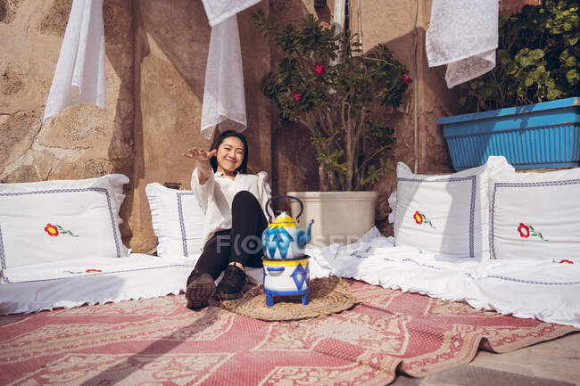 Портрет азиатки, отдыхающей у чайника на полу. Чайная в историческом районе Аль-Фахиди — стоковое фото