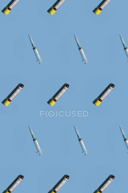 Ansicht von Mosaik oder Muster positiver Bluttests und Spritze vor blauem Hintergrund. — Stockfoto