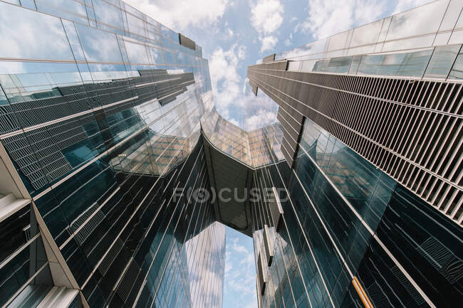 Bas angle de gratte-ciel contemporain à plusieurs étages avec des murs en miroir contre le ciel bleu à Barcelone — Photo de stock