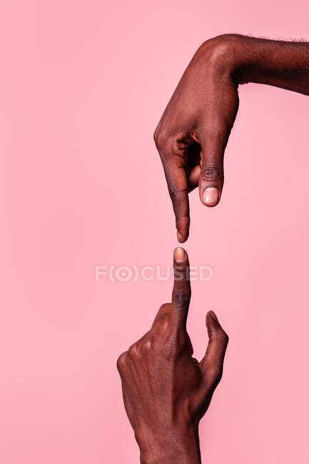 Manos opuestas del hombre afroamericano apuntándose entre sí con el dedo índice aislado sobre fondo rosa - foto de stock